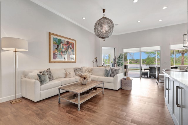 living room featuring an inviting chandelier, ornamental molding, and wood-type flooring