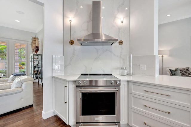 kitchen with high end stainless steel range oven, white cabinets, tasteful backsplash, and wall chimney range hood