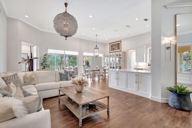 living room featuring ornamental molding, a healthy amount of sunlight, a chandelier, and wood-type flooring