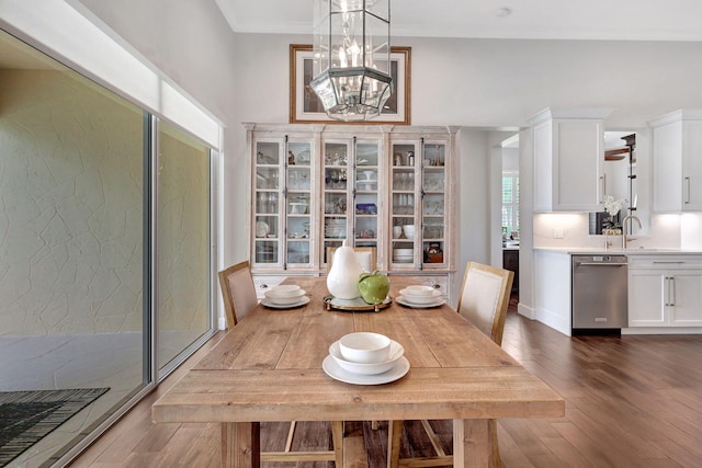 dining space with sink, dark wood-type flooring, ornamental molding, and a chandelier