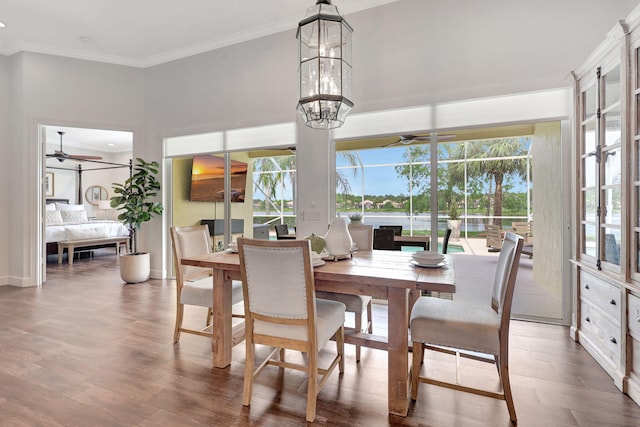 dining area with hardwood / wood-style flooring, ceiling fan with notable chandelier, and ornamental molding