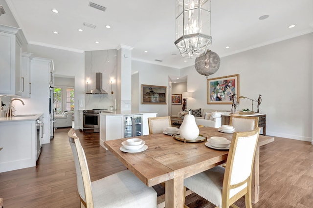 dining area featuring ornamental molding, sink, hardwood / wood-style floors, and a notable chandelier