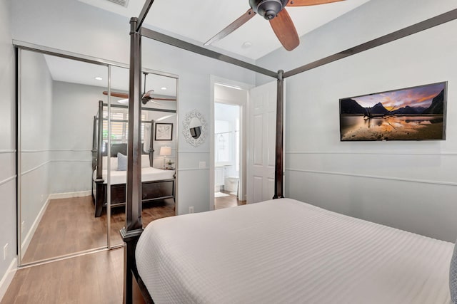 bedroom with ceiling fan, a closet, a barn door, and hardwood / wood-style flooring