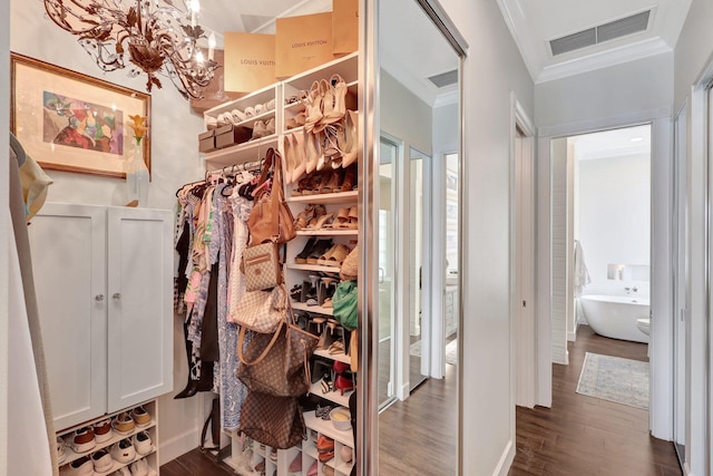 spacious closet featuring dark wood-type flooring and a notable chandelier