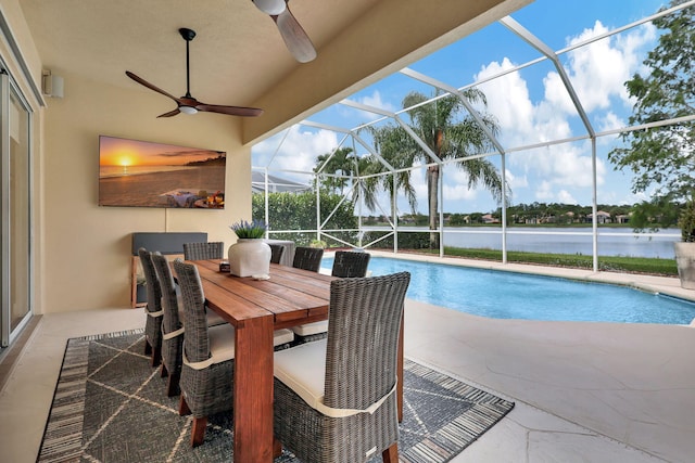 view of pool with a water view, ceiling fan, a patio area, and glass enclosure