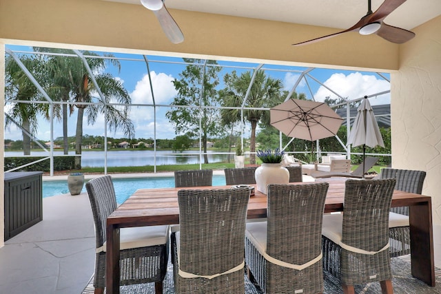 view of patio featuring a water view, ceiling fan, and glass enclosure