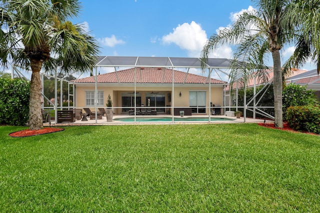 rear view of property featuring ceiling fan, a yard, a patio, and a lanai