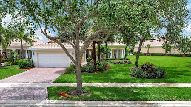 mediterranean / spanish house featuring a garage and a front yard