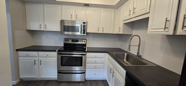 kitchen featuring dark wood-type flooring, decorative backsplash, white cabinetry, appliances with stainless steel finishes, and sink