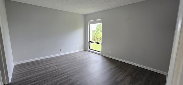 empty room with a textured ceiling and dark hardwood / wood-style floors