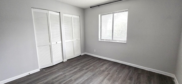 unfurnished bedroom with a textured ceiling and dark wood-type flooring