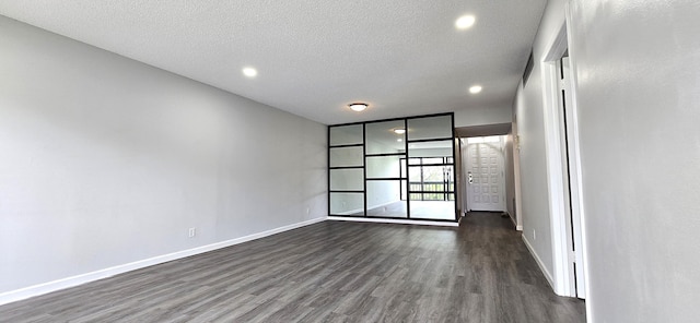 empty room with a textured ceiling and dark hardwood / wood-style floors