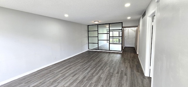 empty room featuring a textured ceiling and dark hardwood / wood-style floors