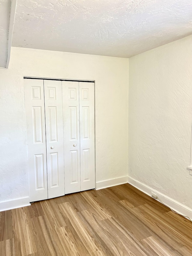 unfurnished bedroom with a closet, a textured ceiling, and light hardwood / wood-style flooring