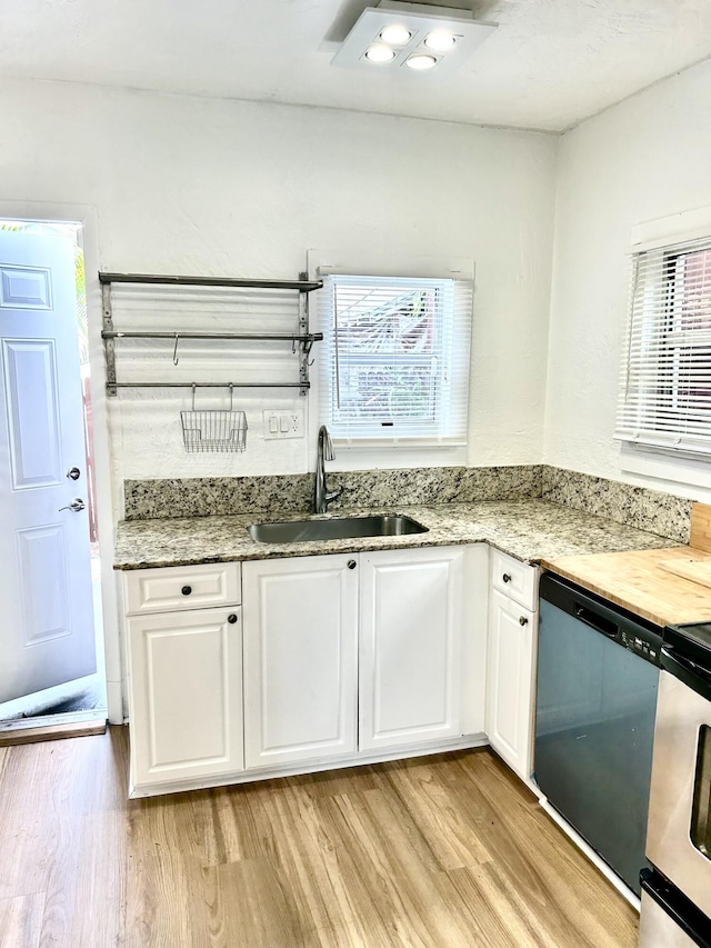 kitchen featuring light stone countertops, sink, light hardwood / wood-style flooring, stainless steel dishwasher, and white cabinets