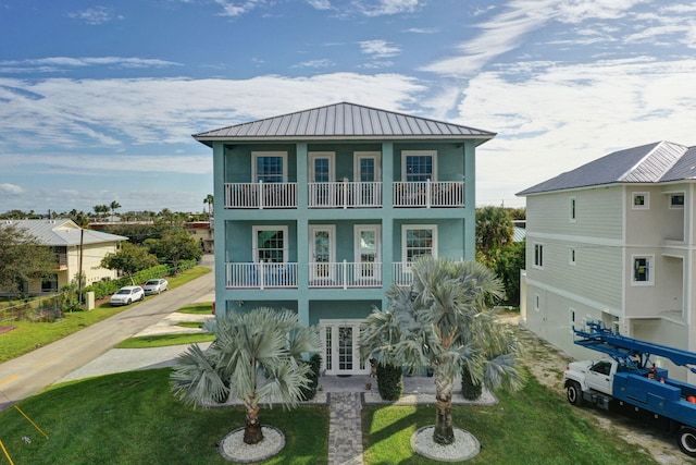 view of front facade featuring a balcony, french doors, and a front yard