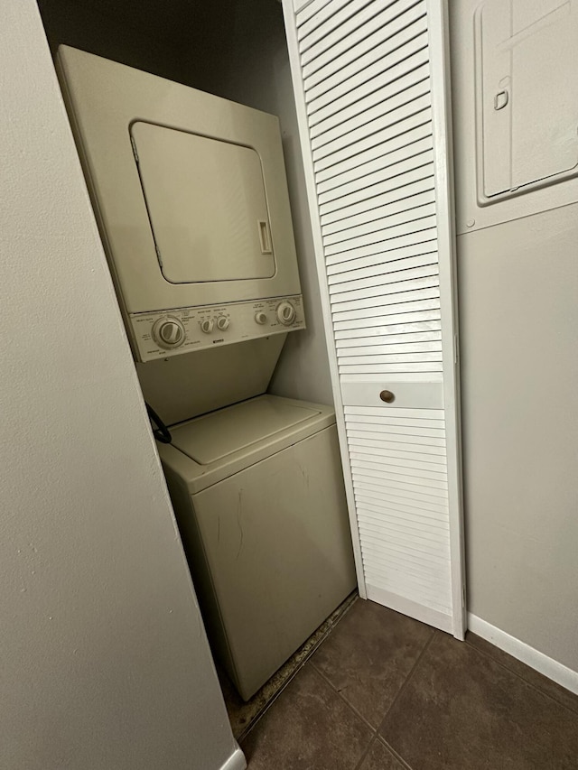 washroom featuring dark tile patterned floors and stacked washer and clothes dryer