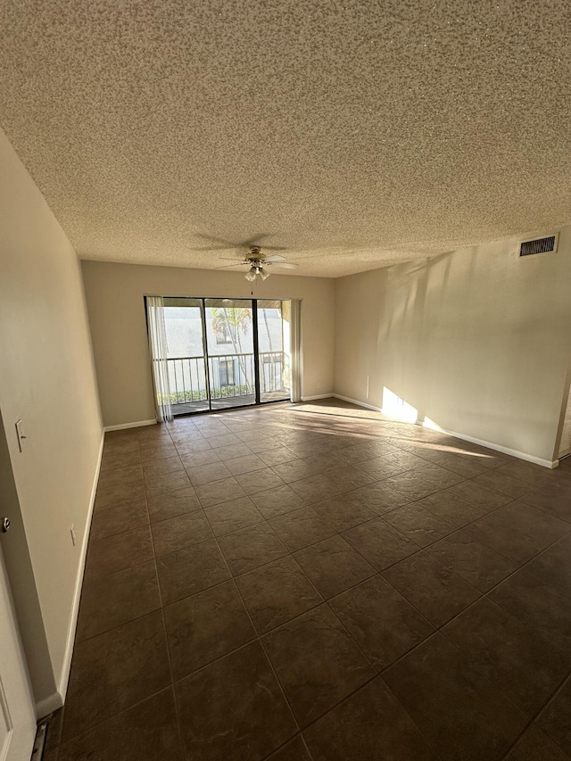 empty room featuring ceiling fan and dark tile patterned flooring