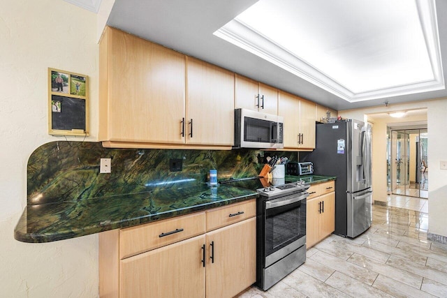 kitchen featuring a raised ceiling, appliances with stainless steel finishes, light brown cabinetry, and decorative backsplash