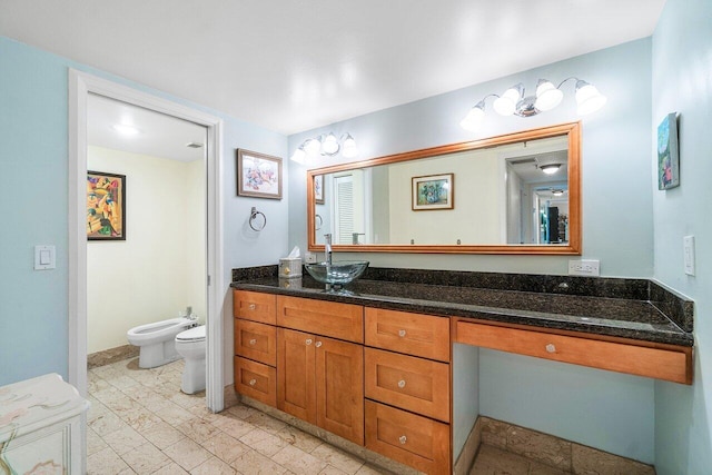 bathroom with a bidet, vanity, and toilet