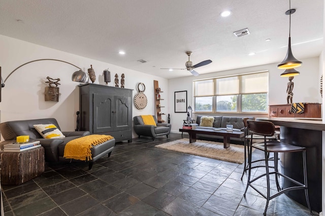 living room featuring a textured ceiling and ceiling fan