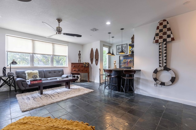 living room with bar area, a textured ceiling, and ceiling fan