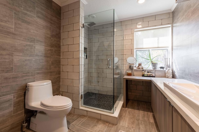 bathroom featuring vanity, crown molding, tile walls, toilet, and a shower with shower door