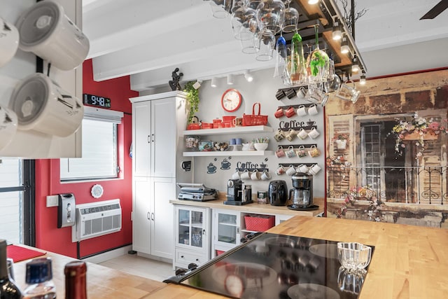 kitchen featuring black electric stovetop, wooden counters, white cabinetry, and beamed ceiling