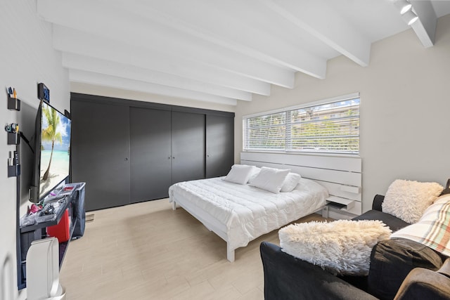 bedroom featuring light wood-type flooring and beam ceiling