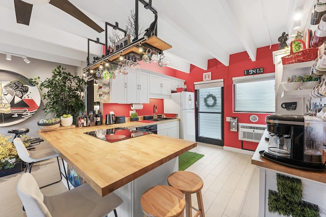 kitchen featuring kitchen peninsula, a breakfast bar, black electric cooktop, beam ceiling, and white cabinets