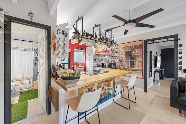 kitchen featuring black electric stovetop, ceiling fan, a kitchen bar, light hardwood / wood-style flooring, and butcher block counters