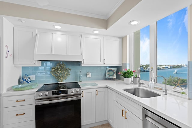 kitchen with appliances with stainless steel finishes, white cabinets, sink, a water view, and wall chimney exhaust hood