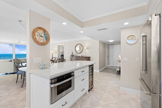 kitchen with white cabinetry, stainless steel appliances, wine cooler, a water view, and crown molding