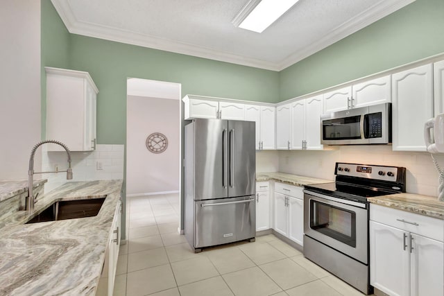 kitchen with white cabinets, stainless steel appliances, light stone countertops, sink, and backsplash