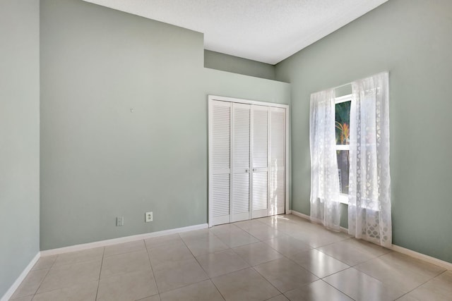 unfurnished bedroom with a textured ceiling, a closet, and light tile patterned flooring