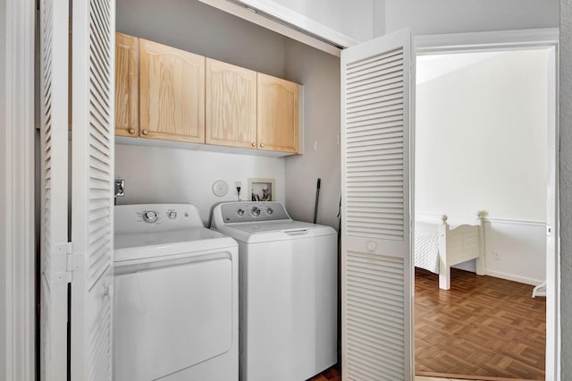 laundry room with dark parquet flooring, washer and clothes dryer, and cabinets