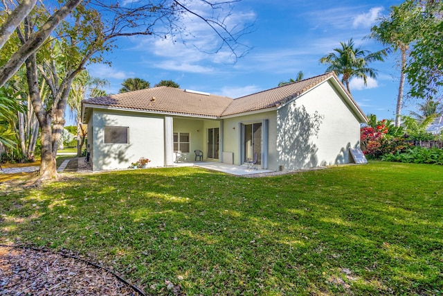 back of property with a lawn and a patio