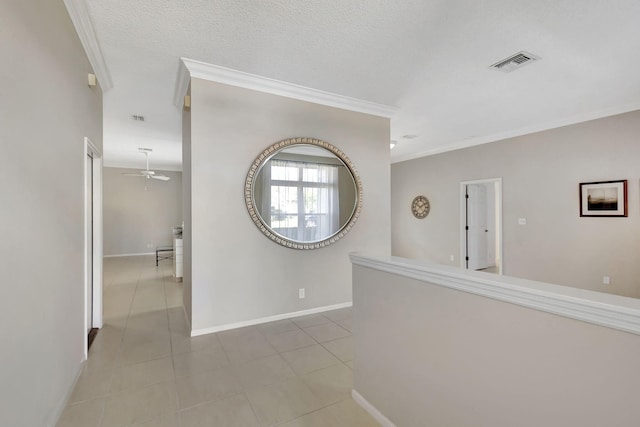 corridor with a textured ceiling, crown molding, and light tile patterned floors