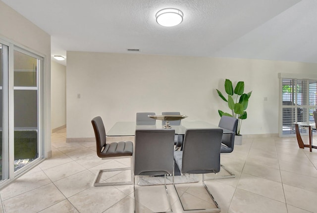 tiled dining room featuring a textured ceiling