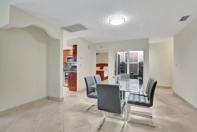 dining space with light tile patterned floors and a textured ceiling