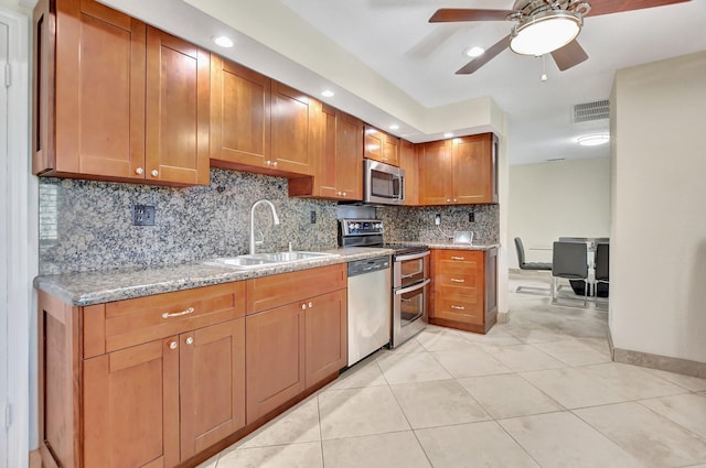 kitchen with ceiling fan, sink, stainless steel appliances, light stone counters, and light tile patterned flooring