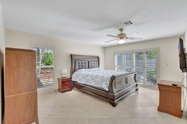 tiled bedroom featuring ceiling fan, access to exterior, and a textured ceiling