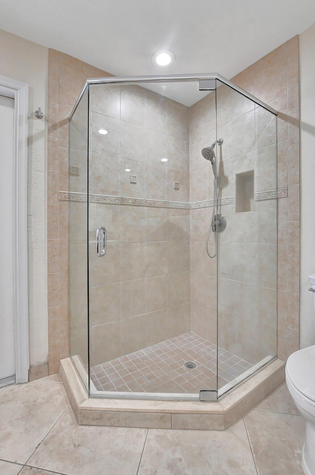 bathroom with tile patterned floors, a shower with door, and toilet