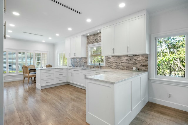 2897 SE Saint Lucie Blvd, Stuart, FL 34997 - kitchen with a sink, white cabinets, light wood-style floors, and a peninsula