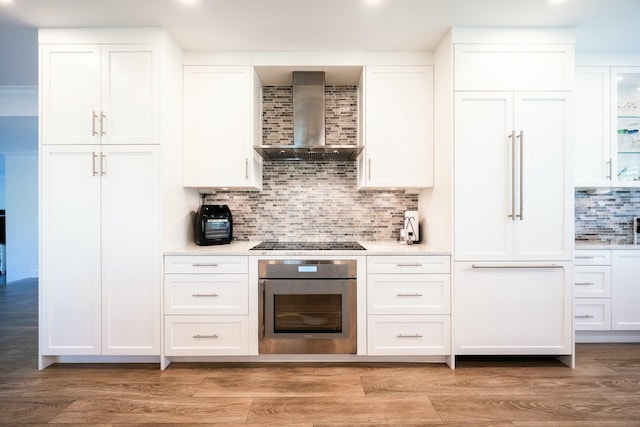 2897 SE Saint Lucie Blvd, Stuart, FL 34997 - kitchen featuring oven, paneled built in fridge, black electric stovetop, wall chimney exhaust hood, and decorative backsplash