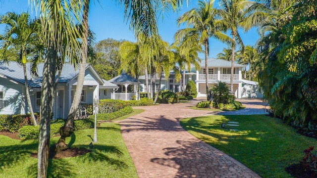 coastal inspired home featuring a gazebo, decorative driveway, and a yard