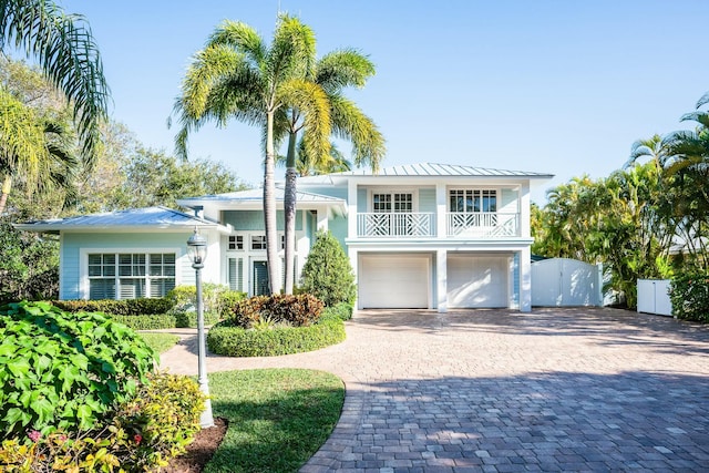 2897 SE Saint Lucie Blvd, Stuart, FL 34997 - view of front of home featuring metal roof, decorative driveway, fence, a balcony, and an attached garage