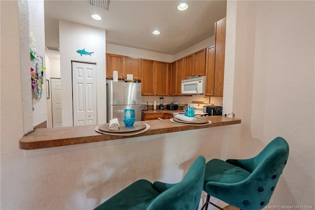 kitchen featuring appliances with stainless steel finishes, a kitchen bar, and kitchen peninsula