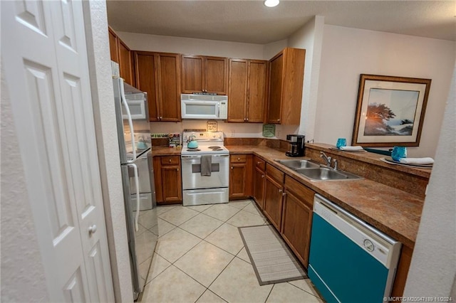 kitchen with sink, light tile patterned floors, and white appliances