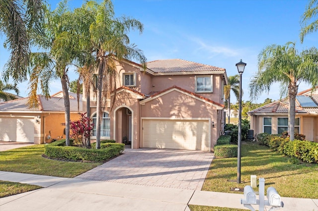 mediterranean / spanish-style house featuring a garage, cooling unit, and a front lawn